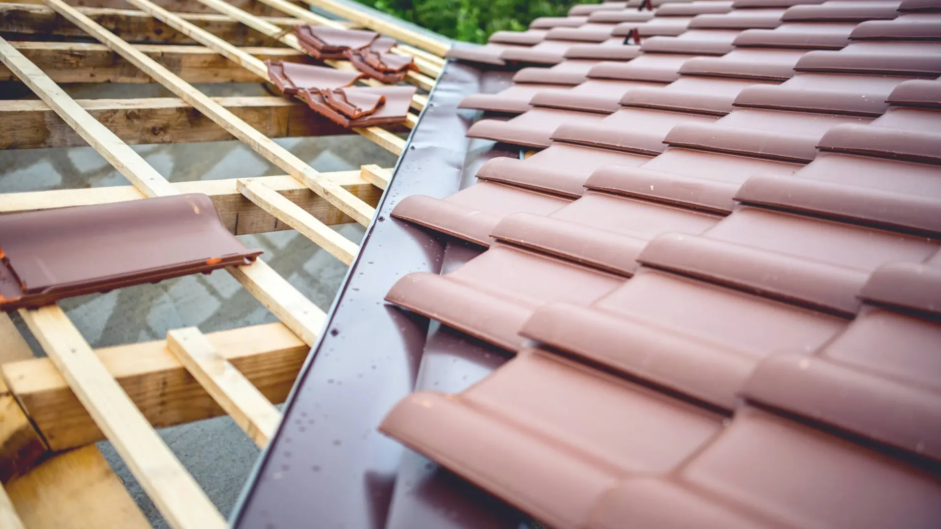 Chantier de pose de tuiles neuves sur une charpente en bois illustrant le choix des matériaux de couverture pour une maison.