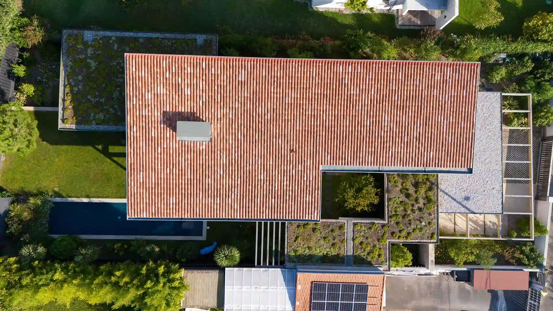 Vue aérienne montrant le contraste de prix au m2 entre une toiture tuiles et une extension végétalisée extensive.