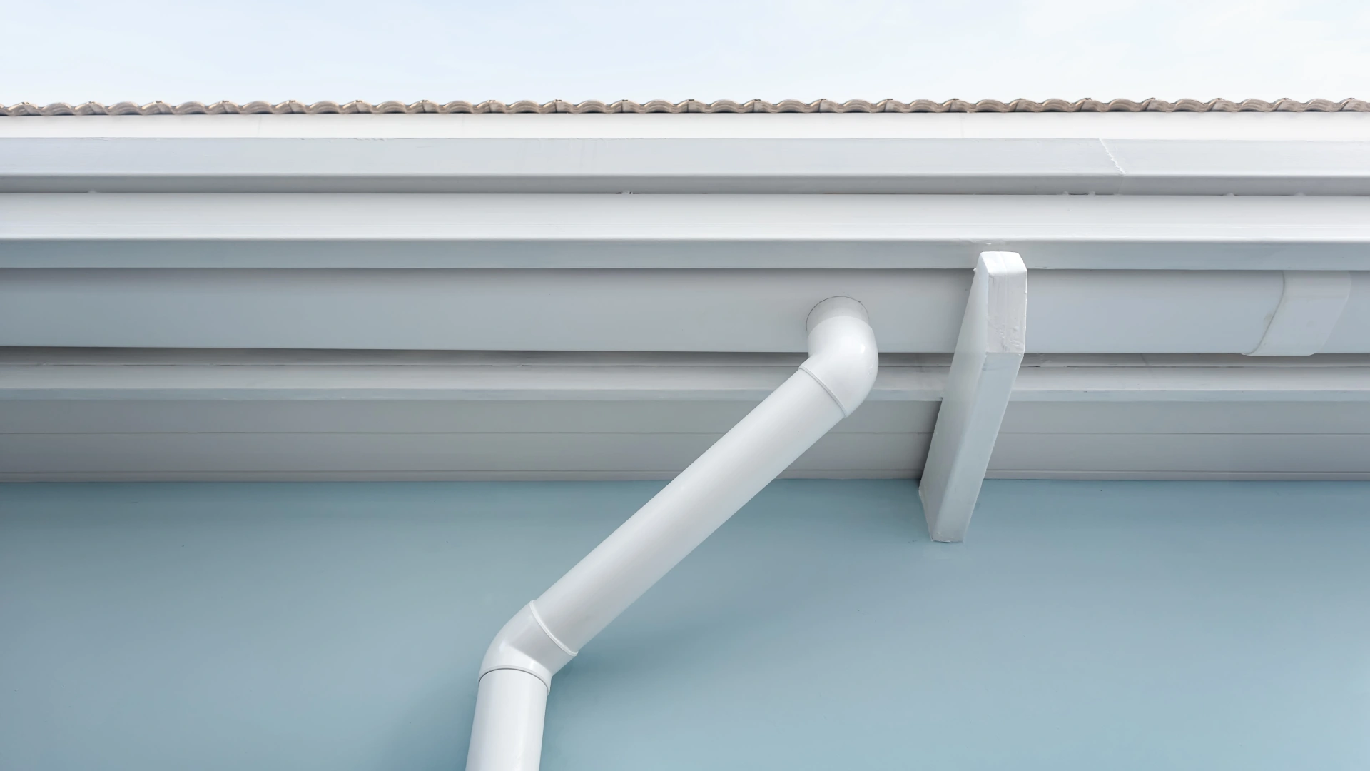 Installation d'une gouttière en PVC blanc avec tuyau de descente, illustrant le prix moyen au mètre linéaire et le coût de pose.