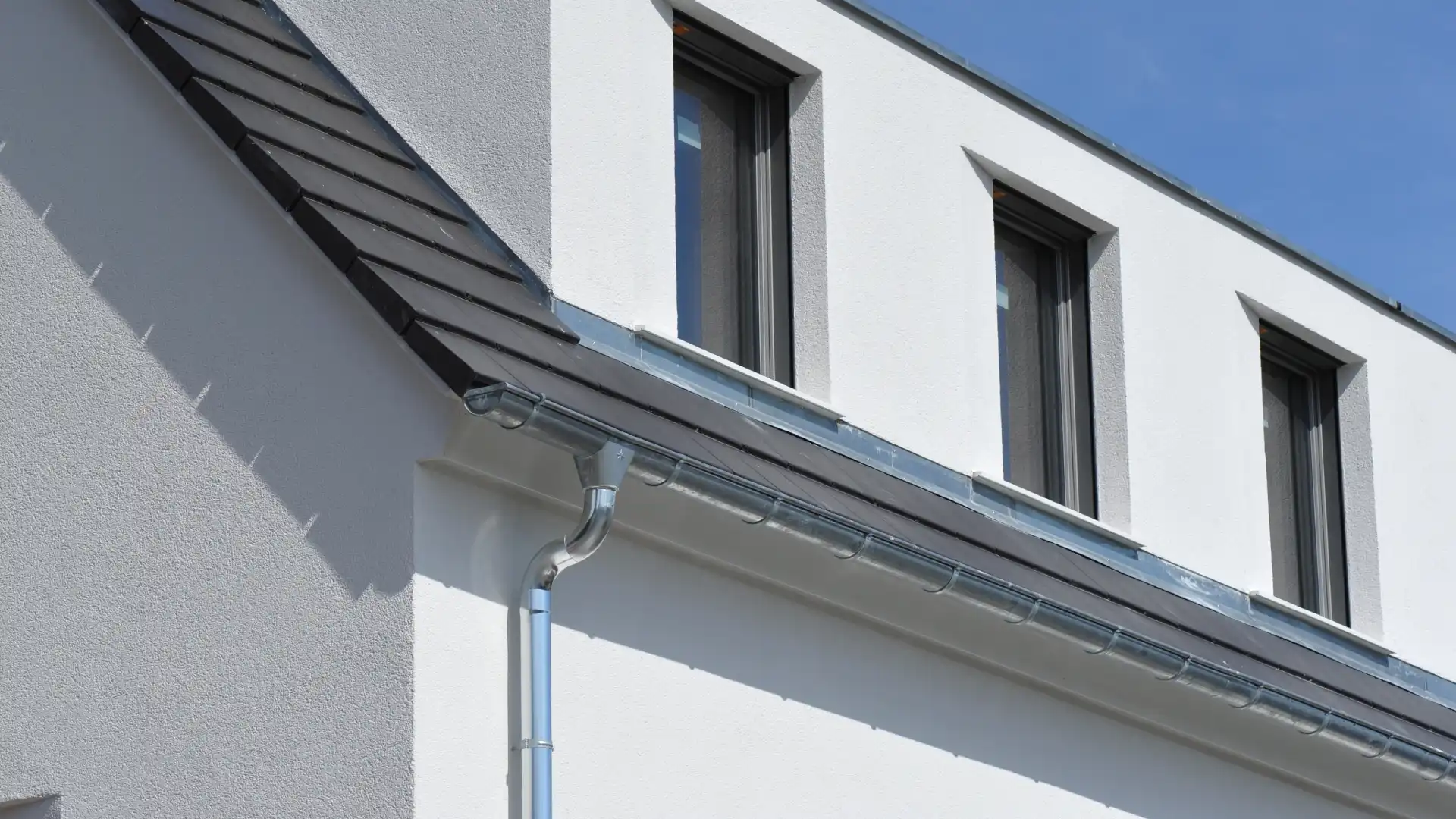 Installation de gouttières en zinc naturel sur une maison moderne, guide des tarifs.